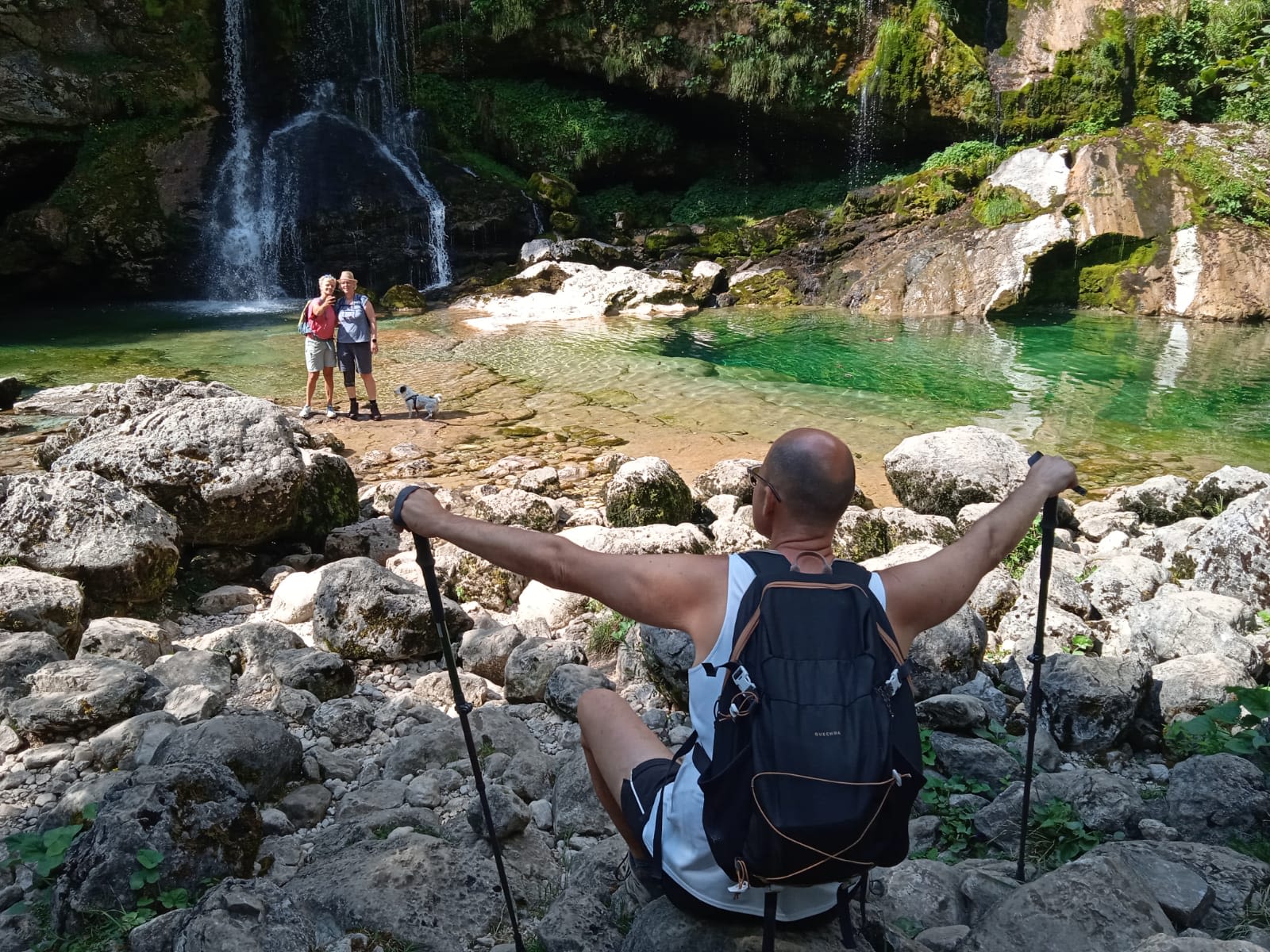 Escursionisti in pausa relax vicino a una cascata, panorama fluviale nel Parco Nazionale del Triglav, Slovenia.